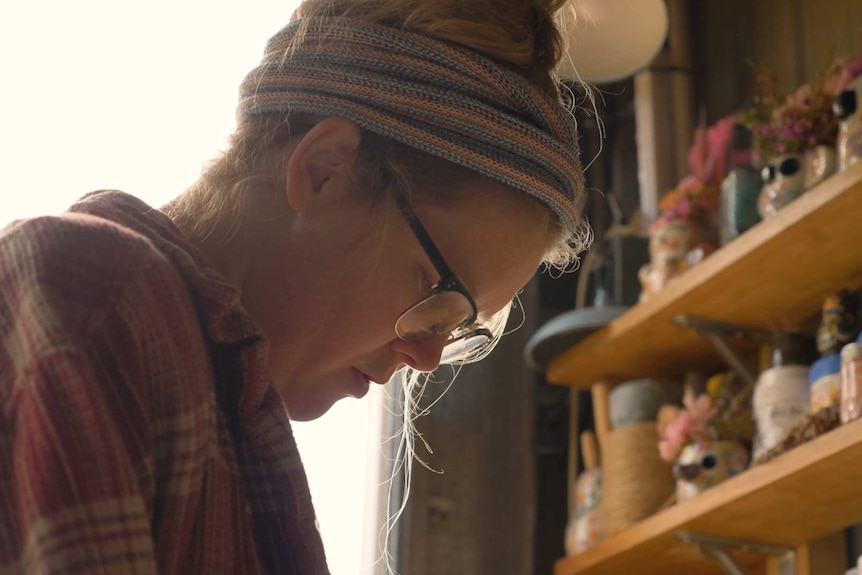 A young blonde woman working in an art studio.