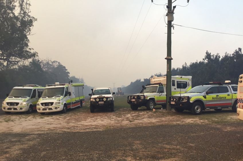 Emergency services vehicles parked with smoke behind them