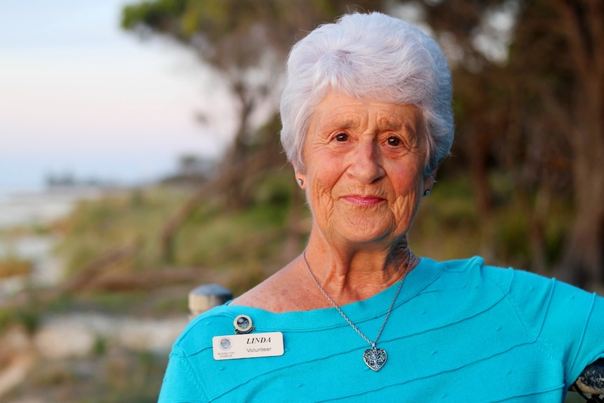 A woman looks at the camera with a neutral expression