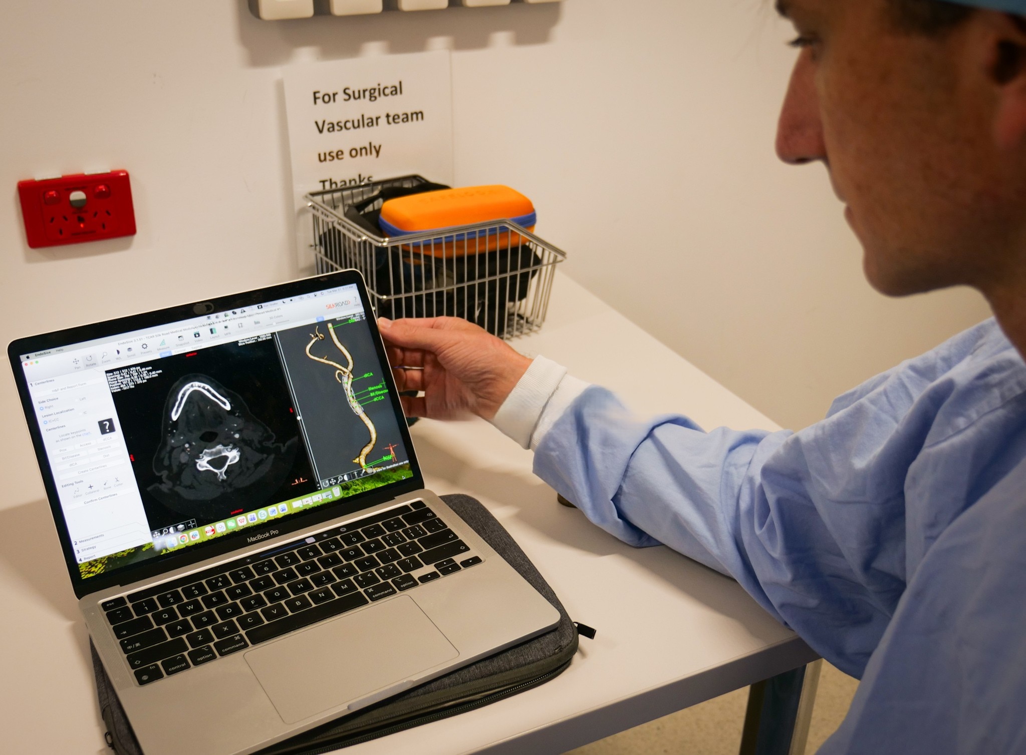 Man in blue scrubs looking at a laptop screen