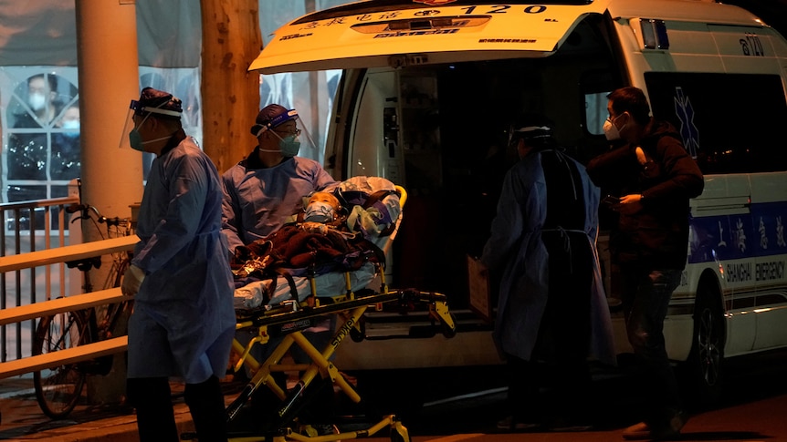 A woman on a stretcher is pushed along by people in blue medical suits. 