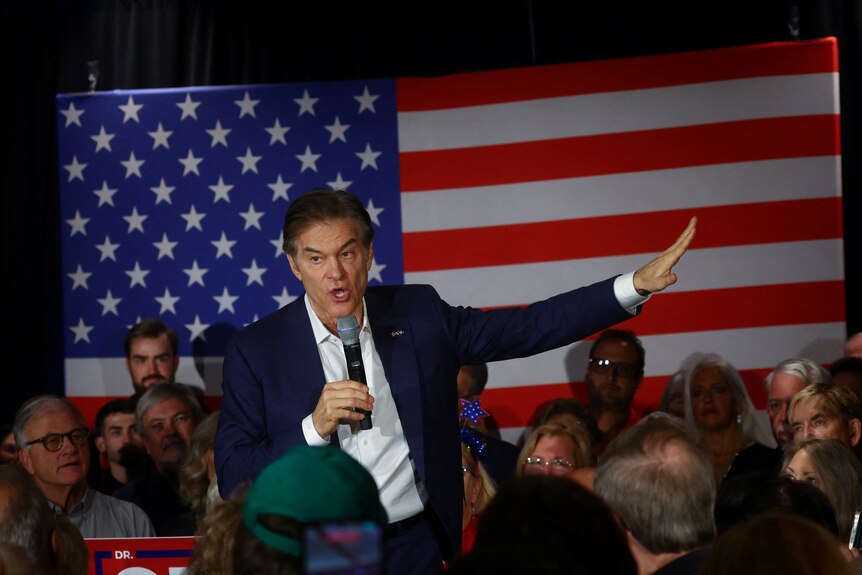 It depicts Dr. Oz speaking into a microphone, with an American flag behind him.
