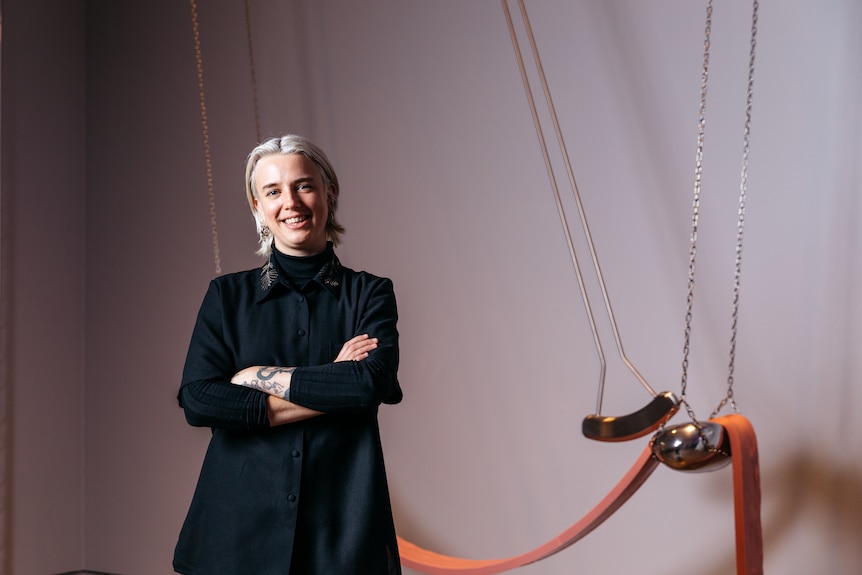 Kate Bohunnis smiles in front of her Ramsay Art Prize winning entry, a kinetic pendulum sculpture 