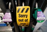 An out of use sign is seen on a pump at a petrol station
