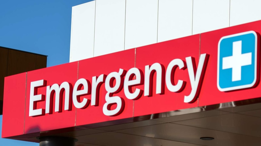 Close up shot of a red "emergency" sign at a Sydney hospital. The sky is blue in the background.