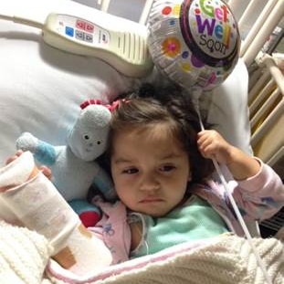 A family photo of Karla shows her lying in a hospital bed, with her arm bandaged, holding a balloon that reads "get well soon".