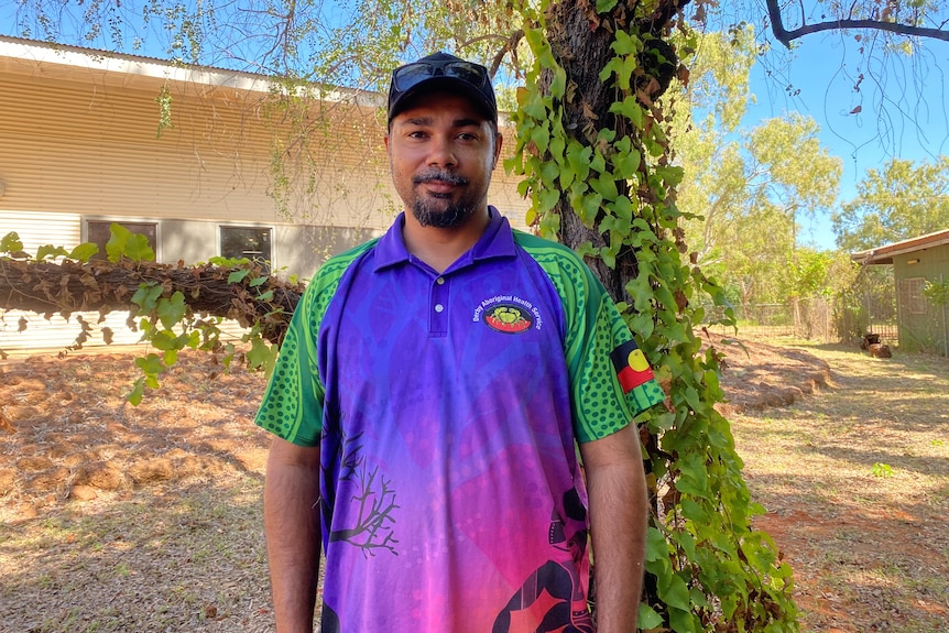 An aboriginal man standing in front of a tree