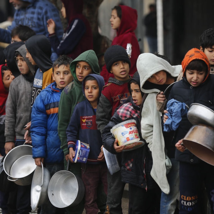 Palestinian children in a queue holding saucepans