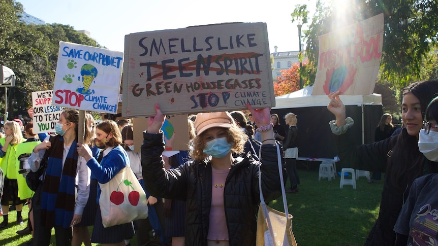 A young protester stands at a climate change rally in Melbourne, holding up a sign.