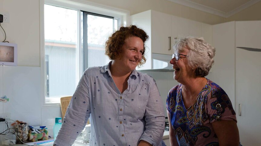 Two women stand in a kitchen laughing