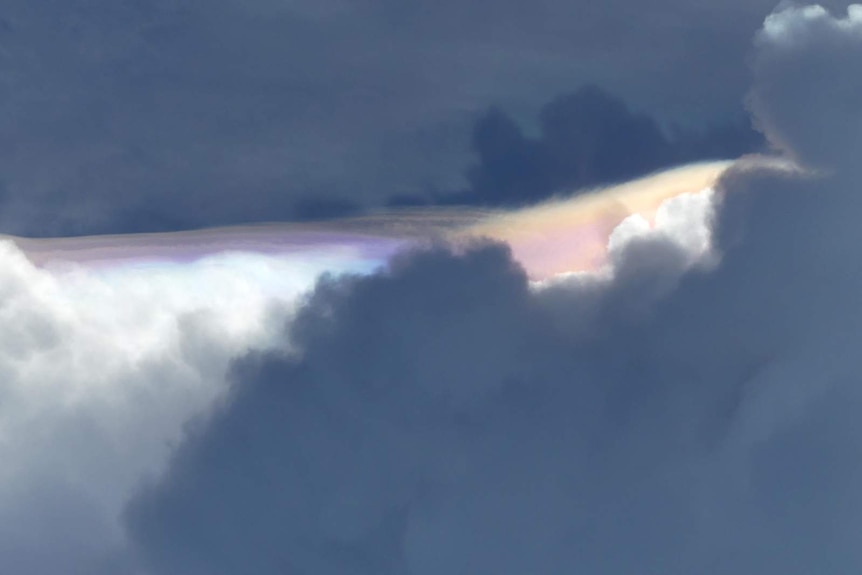A photograph of the unique rainbow sandwiched between layers of dark cloud.
