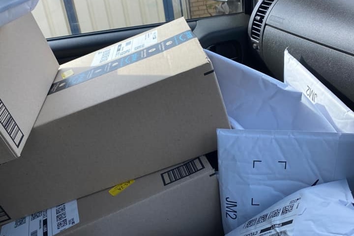 Amazon packages are stacked high on the front passenger seat of a car.
