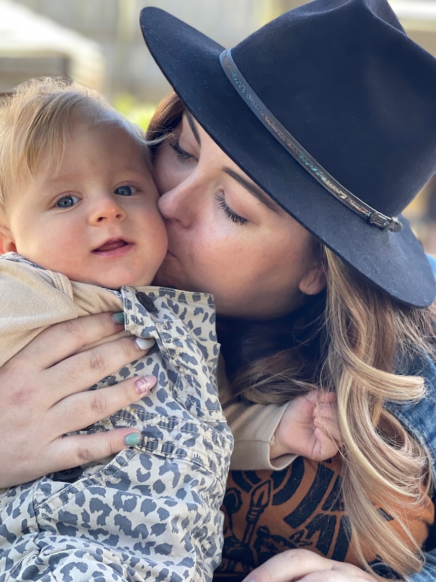 woman with hat kissing baby