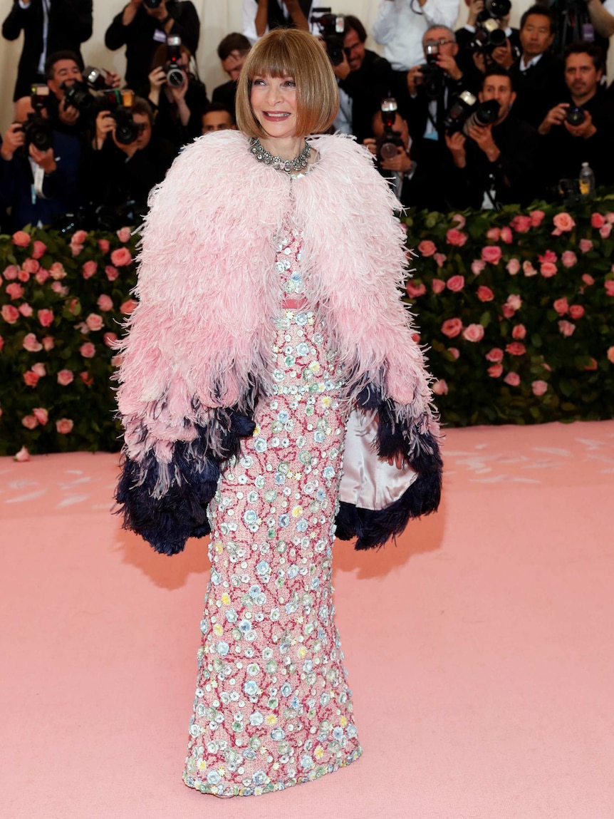 Wintour wears a pink fluffy cape with a sequinned gown