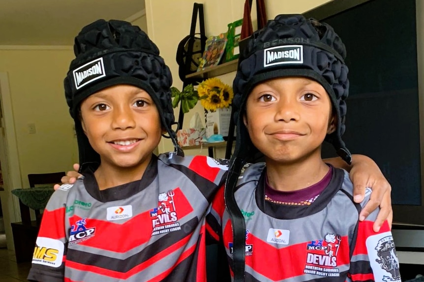 Two young twin boys in black headgear and black and red shirts