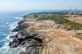 A rugged coastline showing cliffs and wind turbines