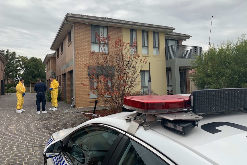 three forensic officers outside a townhouse