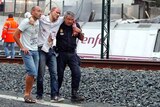 Rescue workers help a victim walk away after a fatal train crash in Spain