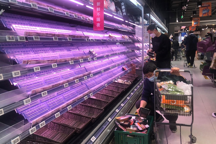 Two men look through empty deli shelves at a supermarket in Shanghai, 