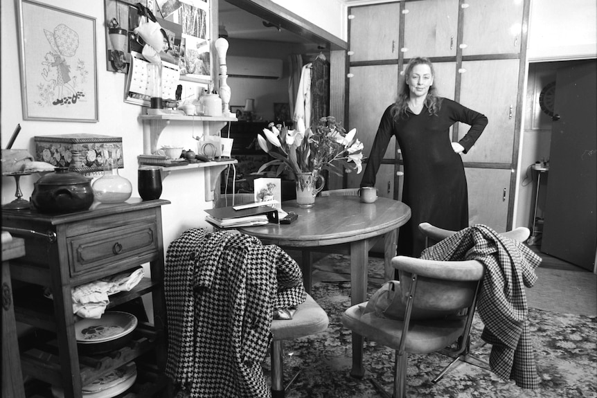 a black and white  picture of a woman standing in a country style kitchen