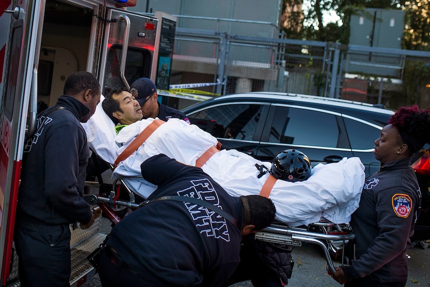 Emergency personnel carry a man into an ambulance