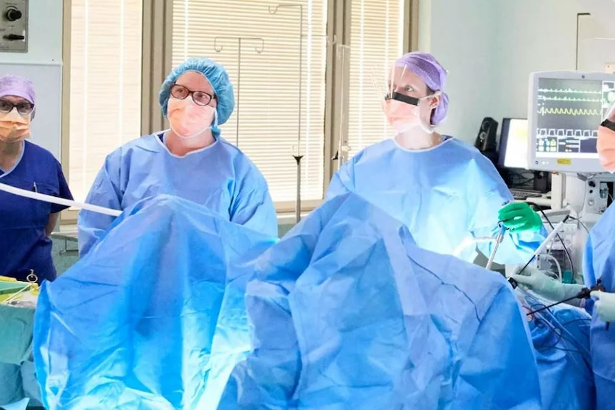 Surgeons in scrubs in an operating theatre.