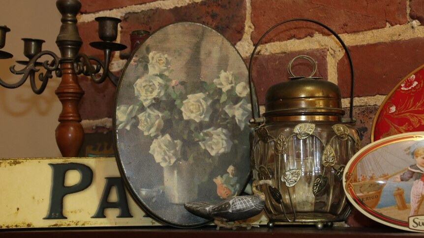 The tin and other items resting on the mantlepiece of a brick fire place