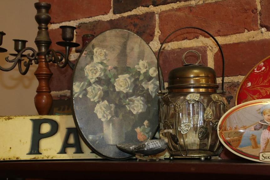 The tin and other items resting on the mantlepiece of a brick fire place