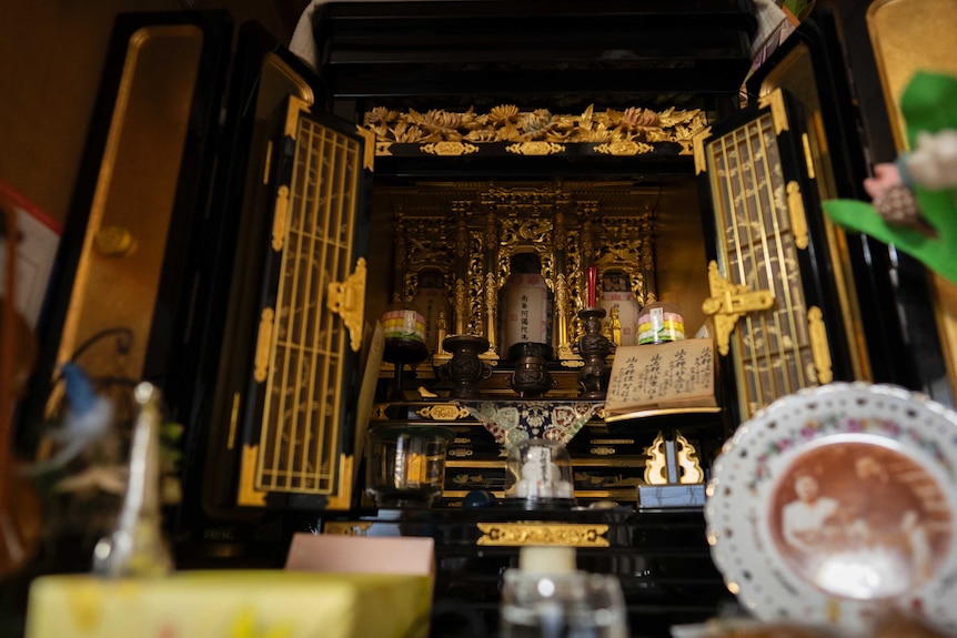 A golden Japanese shrine with photos and candles placed in front of it