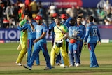 A batsman walks off after a Cricket World Cup match, as the opposing team stand on the pitch.