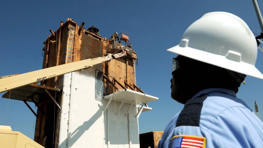 A security guard watches as workers put the finishing touches on the Pollution Control Dome