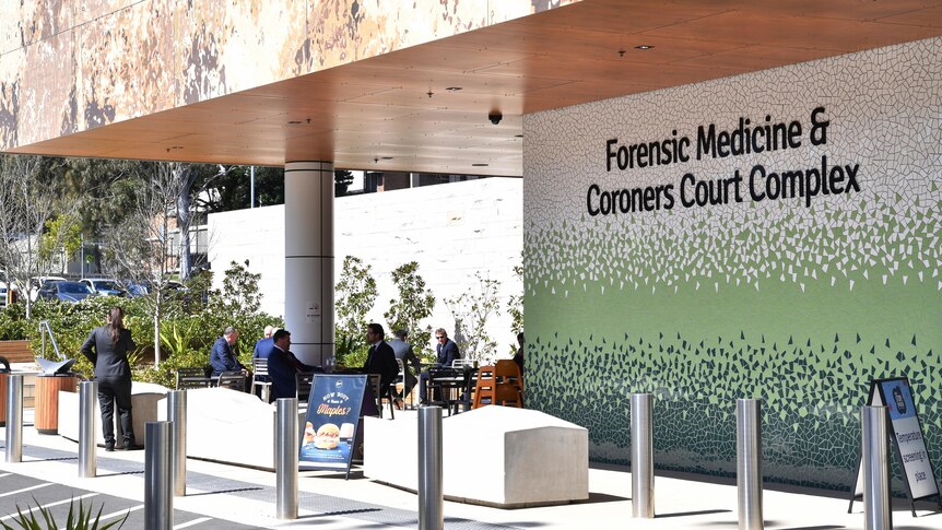 The modern-looking facade of a building bearing the lettering "Forensic Medicine and Coroners Complex".