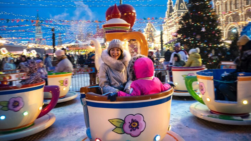 A woman and child spin on a tea cup ride in Red Square.