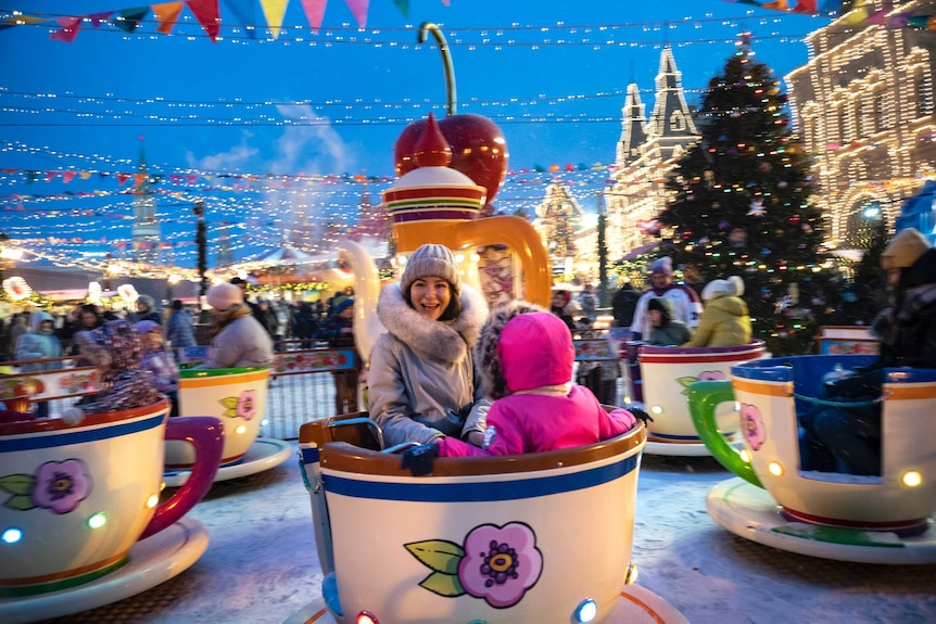 A woman and child spin on a tea cup ride in Red Square.