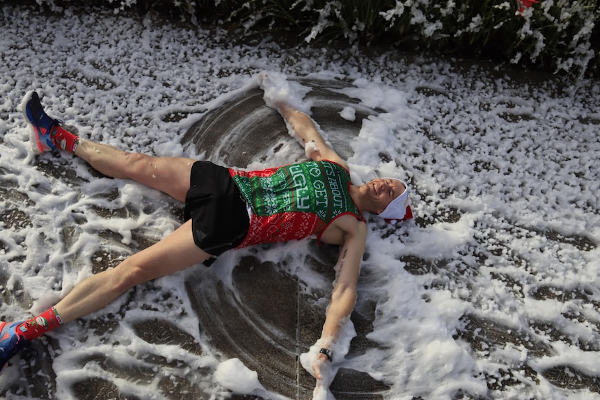 A runner lies down in the fake snow