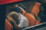 Man slumped over in bus looking miserable