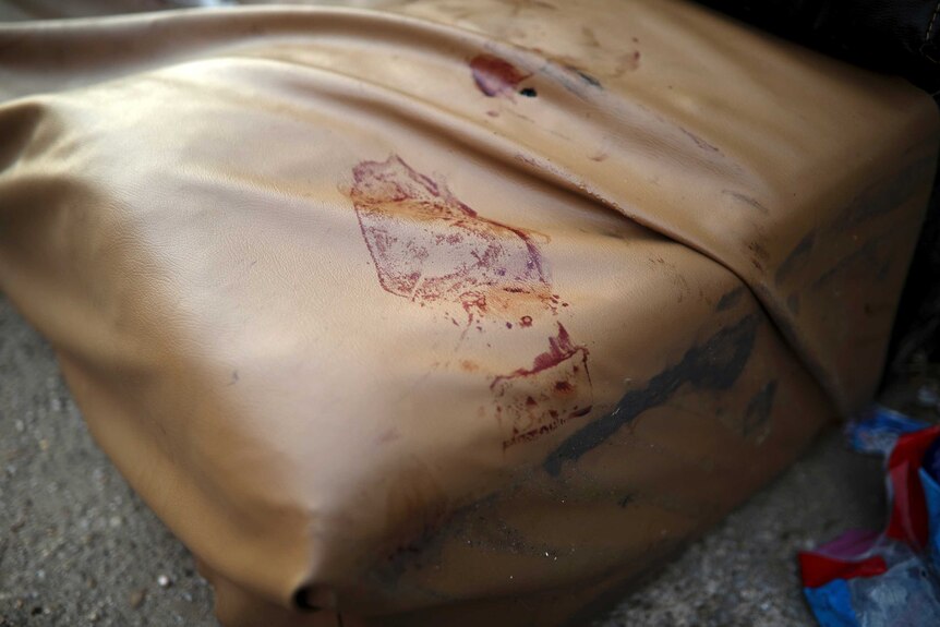 A bloody shoe print on a tan-coloured couch can be seen.