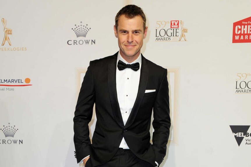 Roger Corser wears a black and white suit and tie on the logies red carpet.