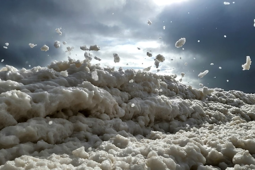 A wall of foam around 1 metre high along the shoreline