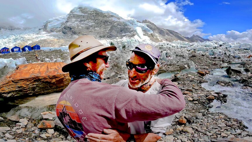 two men hug on a mountain