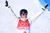 Laura Peel holds her arms in the air and smiles as she skis at the bottom of the hill