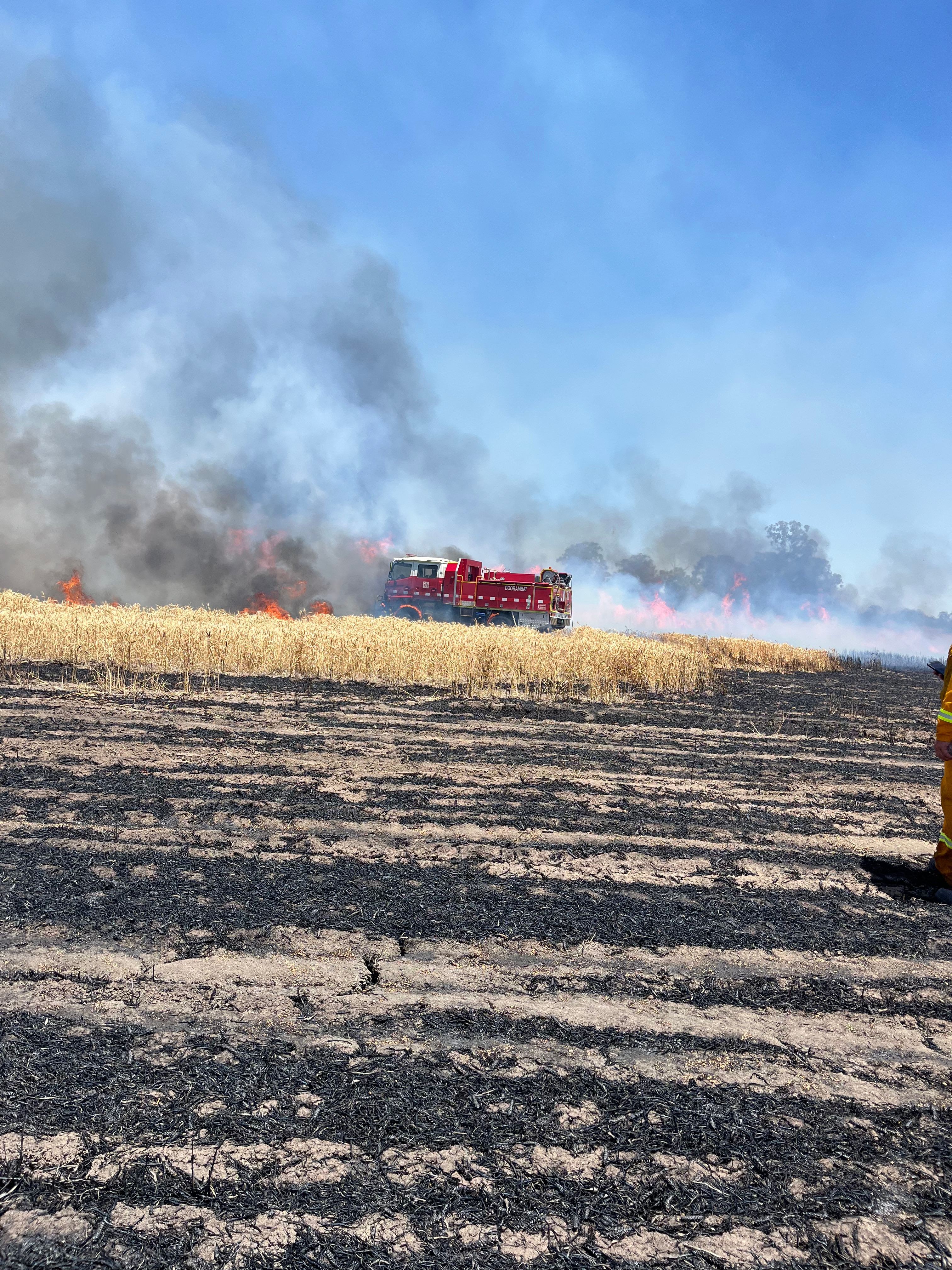 Un camión de bomberos en un prado quemado con humo y llamas