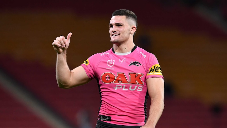 Nathan Cleary gives a thumbs up to fans and smiles in pink Penrith jersey.