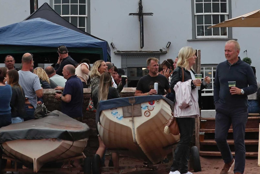 People stand in foreground of a pub drinking beer