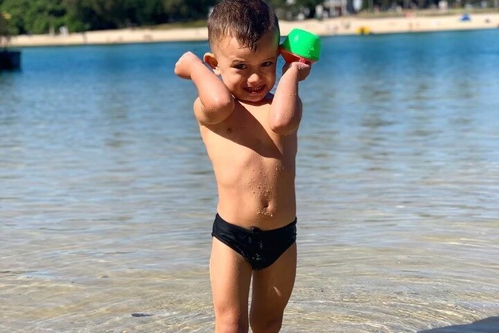 Trey wearing bathers stands in water at the beach
