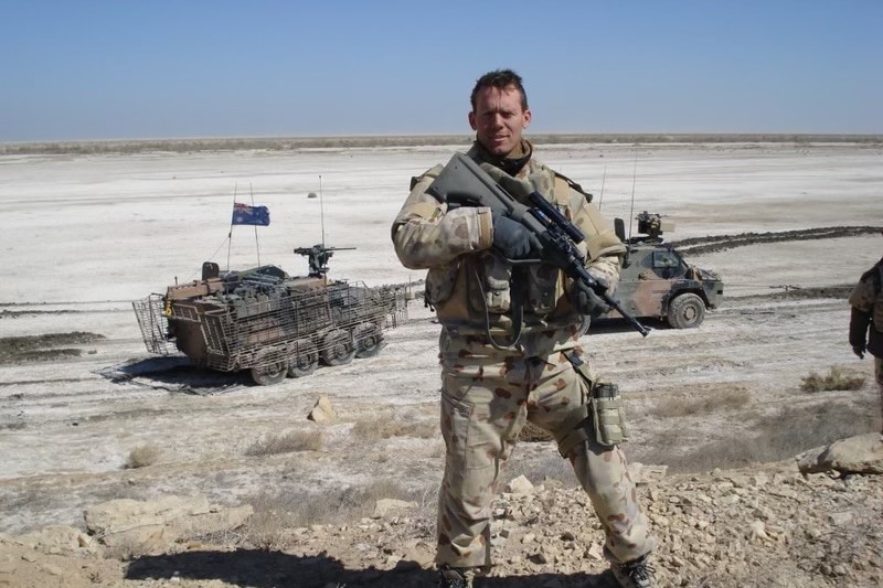 A soldier standing in the desert with a rifle