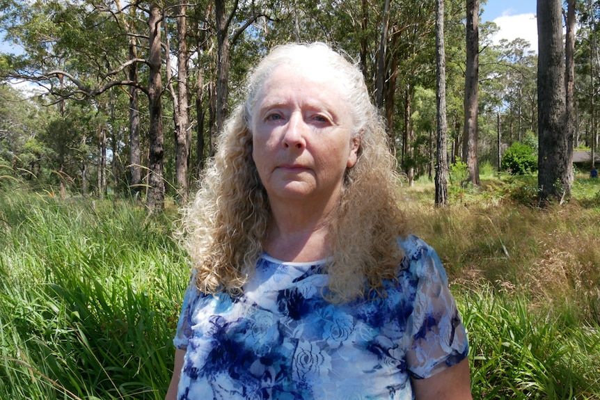Woman stands in bush-land with a blue top