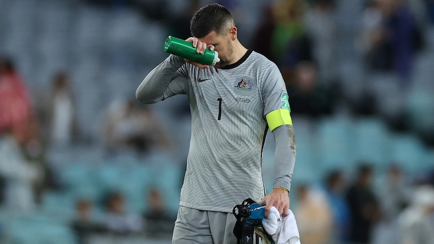 The Socceroos' goalkeeper holds his right hand to his forehand after losing to Japan.