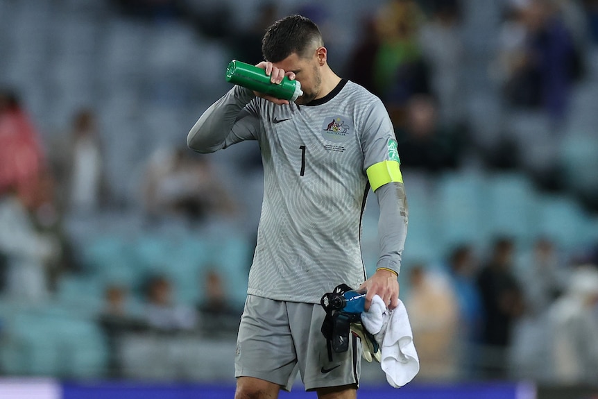 The Socceroos' goalkeeper holds his right hand to his forehand after losing to Japan.