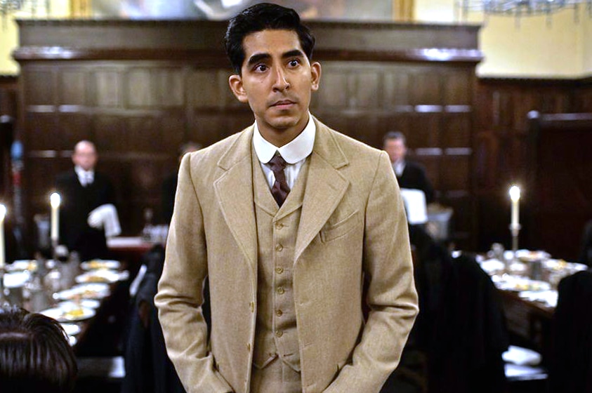 A man of South Asian descent wearing a brown-coloured suit with a white short and black tie underneath